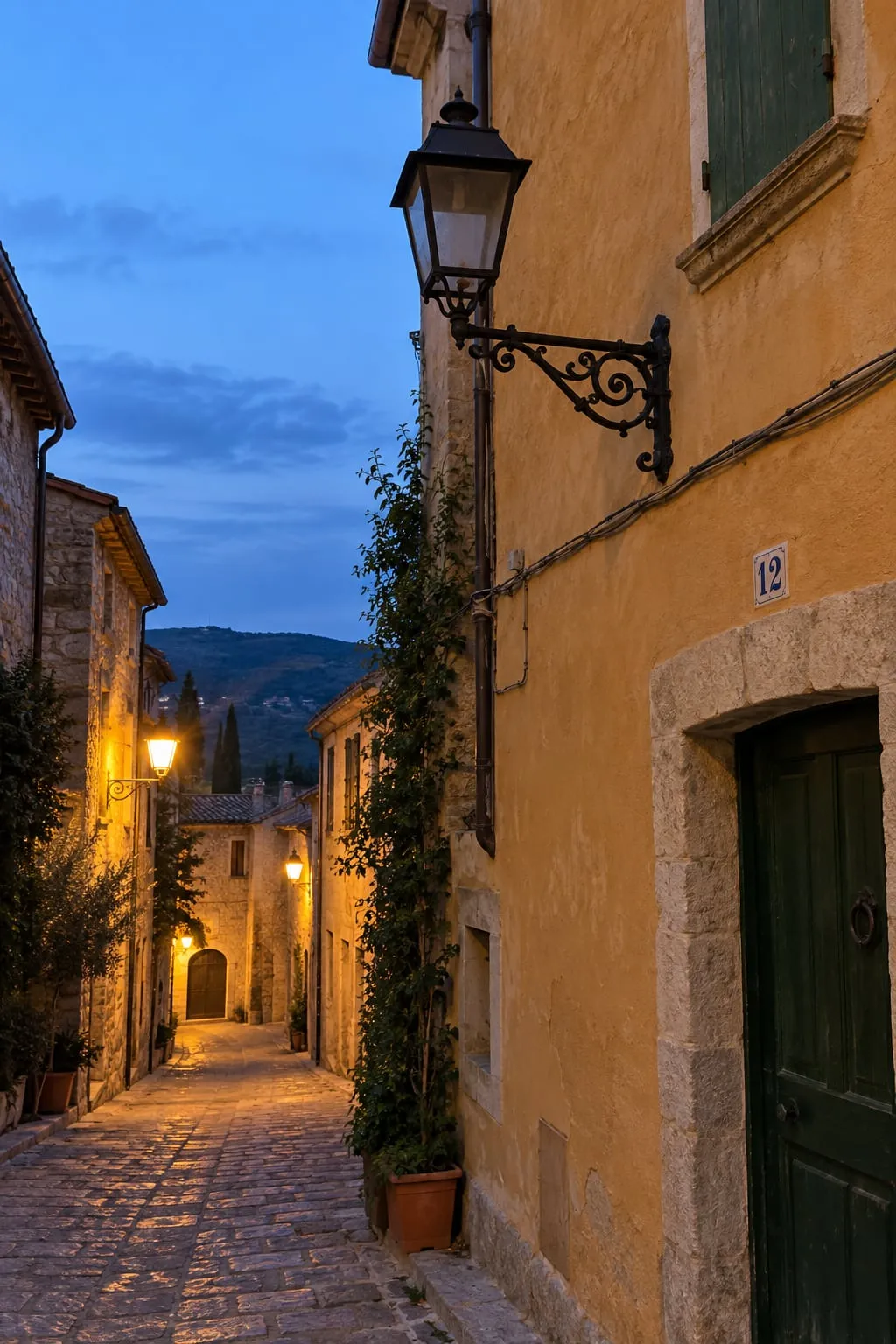 Carrer de pedra al vespre amb un fanal de forja apagat al costat del número 12